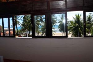 una finestra con vista sulla spiaggia e sulle palme di Casa Praia Cai Nagua 8/4 a Olivença