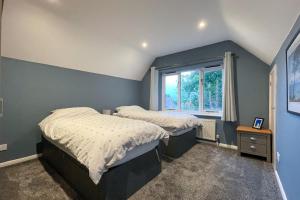 a bedroom with two beds and a window at Surrey Hills Lodge in Ewhurst