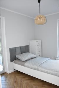 a bed in a bedroom with a white wall at Apartament pod zegarem in Giżycko