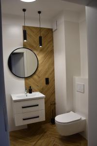 a bathroom with a white toilet and a mirror at Apartament pod zegarem in Giżycko