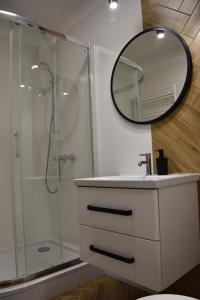 a bathroom with a sink and a shower with a mirror at Apartament pod zegarem in Giżycko