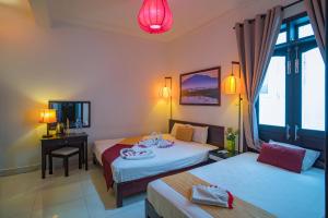 a hotel room with two beds and a desk and a window at The House 36 in Hoi An +38 photos