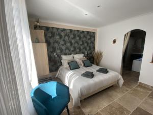 1 dormitorio con 1 cama y 1 silla azul en Chambre d'hôtes Alizé, Le Moulin de Prédelles en Reillanne