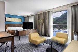um quarto de hotel com uma cama e uma grande janela em Four Points Sheraton Bolzano Bozen em Bolzano