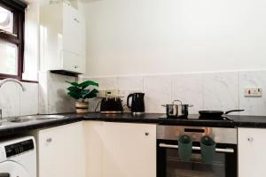 a kitchen with white cabinets and a stove top oven at Cosy decorated flat in Tonbridge in Tonbridge
