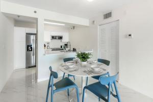 a white dining room with a table and blue chairs at Brickell Bay View Oasis with Pool Hot Tub and Gym in Miami