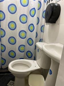 een badkamer met een toilet, een wastafel en een douchegordijn bij Casa Hotel La Palmera Apartadó in Apartadó