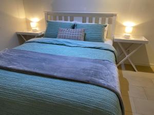 a bed with a blue blanket and two night stands at Darwin Waterfront Luxury Condo in Darwin