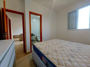 um quarto com uma cama grande e uma janela em Apartamento com piscina aquecida e churrasqueira em Ubatuba mais 26 fotografias