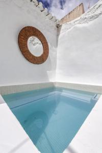 einem Pool in einem weißen Gebäude mit kreisförmigem Fenster in der Unterkunft Encanto Guesthouse in Canillas de Aceituno