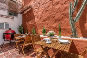 un patio con mesa, sillas y cactus en Encanto Guesthouse, en Canillas de Aceituno
