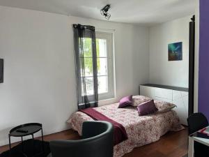a bedroom with a bed with purple pillows and a window at L’Escale: Appartement complet in Tours