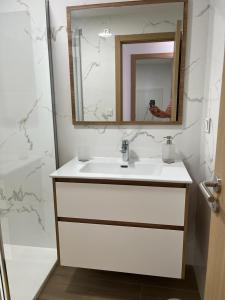 a bathroom with a white sink and a mirror at Apartamento Gallaecia Lux in Santiago de Compostela