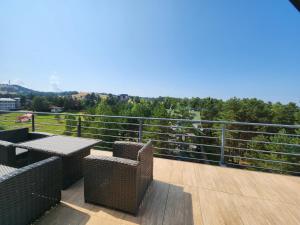 a balcony with tables and chairs and a view at LUX Apartman Simi in Divčibare