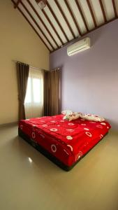 Cama roja en habitación con ventana en Rumah Yosua, en Palbapang