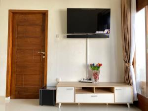 a living room with a tv on the wall and a door at Rumah Yosua in Palbapang