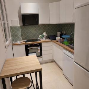 a kitchen with white cabinets and a table in it at BLUMENTHAL in Épinay-sur-Seine +5 photos