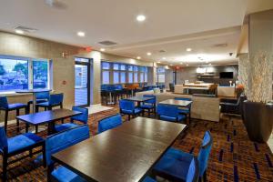 a restaurant with wooden tables and blue chairs at Courtyard Cape Cod Hyannis in Hyannis