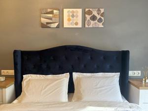 a bed with a blue headboard and three paintings on the wall at elisio - Bricks Apartment in Braşov