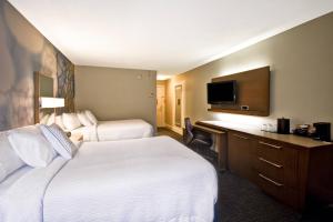 a hotel room with two beds and a desk and a television at Courtyard Cape Cod Hyannis in Hyannis