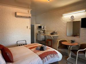 a hotel room with a bed and a table and a kitchen at Jillaroo Motor Inn in Glen Innes