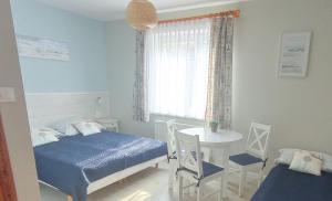 a bedroom with two beds and a table and a window at Szanta in Jastarnia
