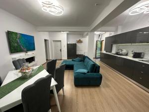 uma sala de estar com um sofá azul e uma cozinha em Agi’s Apartment Predeal em Predeal