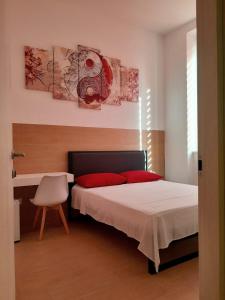una camera da letto con letto con cuscini rossi e scrivania di Piazza Teatro Apartments & Rooms a Trani