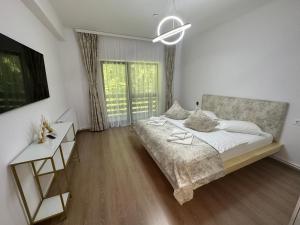 a white bedroom with a bed and a desk and window at Agi’s Apartment Predeal in Predeal