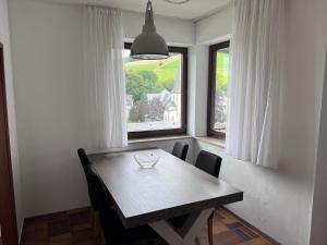 einen Esstisch mit Stühlen und ein Fenster in der Unterkunft Vakantiewoning Paula Sauerland in Schmallenberg