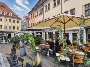 a group of people sitting at tables under an umbrella at Altstadt Domizil in Pirna