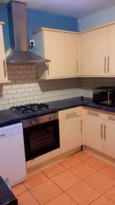 a kitchen with white cabinets and a black stove top oven at Transformative housing Laurie avenue in Nottingham