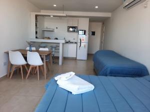 a room with two beds and a table and a kitchen at M O R A Home & Office in Cipolletti