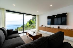 ein Wohnzimmer mit zwei Sofas und einem großen Fenster in der Unterkunft Villa Rocha in Arco da Calheta in Arco da Calheta