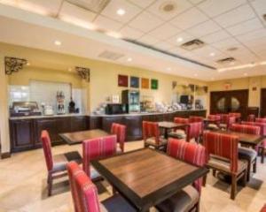 a restaurant with wooden tables and red chairs at Comfort Suites Miami - Kendall in Kendall