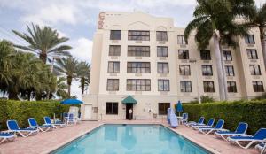 ein Hotel mit Stühlen, einem Pool und einem Gebäude in der Unterkunft Comfort Suites Miami - Kendall in Kendall