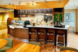 une cuisine avec un bar et des tabourets dans un restaurant dans l'établissement Courtyard by Marriott Lansing, à Lansing