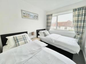 two beds in a room with a window at Cae Glas Apartments in Holyhead
