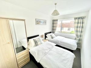 a bedroom with two beds and a mirror at Cae Glas Apartments in Holyhead