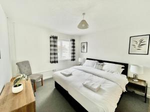 a bedroom with a large white bed and a desk at Cae Glas Apartments in Holyhead