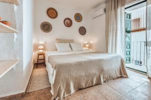 a white bedroom with a bed and a large window at Encanto Guesthouse in Canillas de Aceituno
