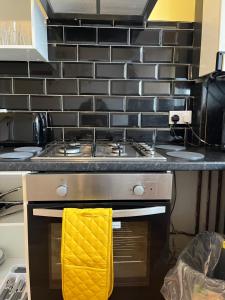 La cocina está equipada con fogones y una toalla amarilla. en 2 bedroom apartment, 5 minutes from city centre, en Newcastle