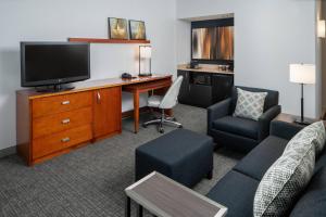 a living room with a tv and a couch and a desk at Courtyard by Marriott Dulles Airport Herndon/Reston in Herndon