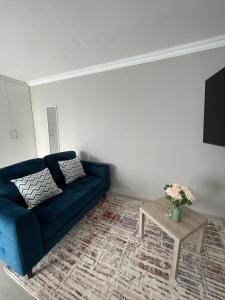 een woonkamer met een blauwe bank en een tafel bij Spacious stay-in bachelor apartment in Kempton Park