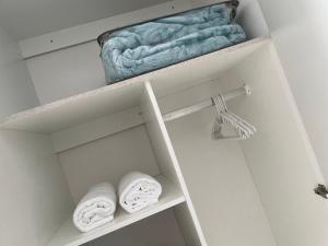 een witte kast met twee handdoeken op een plank bij Spacious stay-in bachelor apartment in Kempton Park