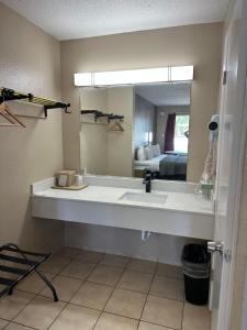 uma casa de banho com um lavatório e um espelho grande em Travelers Rest Motel em Bogalusa