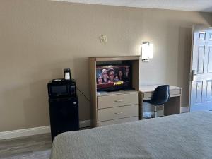 um quarto de hotel com uma televisão, uma cama e uma secretária em Travelers Rest Motel em Bogalusa