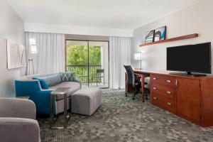 Courtyard Sarasota Bradenton Airport في ساراسوتا: غرفة في الفندق مع أريكة وتلفزيون ومكتب