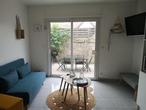 un salon avec un canapé bleu et une table dans l'établissement Appartement 4 personnes à louer, à Ouistreham