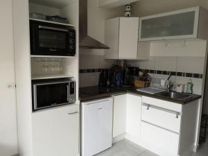 une cuisine avec des armoires blanches et des appareils noirs dans l'établissement Appartement 4 personnes à louer, à Ouistreham